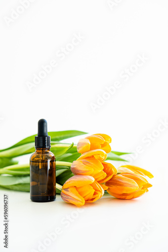 Amber glass cosmetic dropper bottle and orange tulips isolated on white background  serum bottle mockup