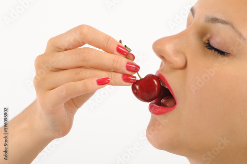 Young woman eating cherry. Isolated on a white background.
