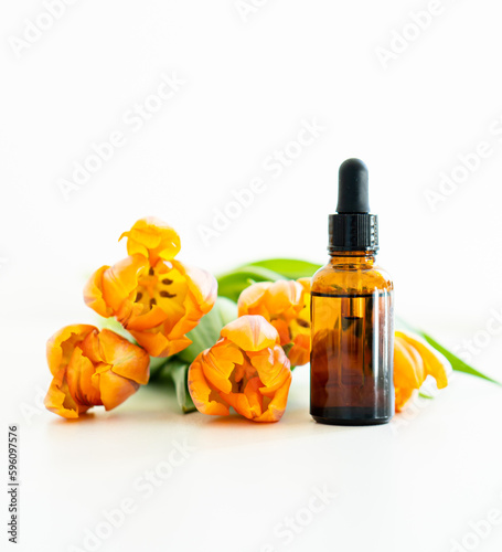 Amber glass cosmetic dropper bottle and orange tulips isolated on white background, serum bottle mockup