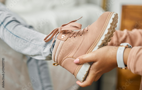 It fits perfectly. an unrecognizable person putting a shoe onto a childs foot at home.