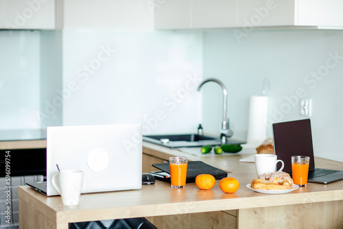 Modern kitchen without people with wooden work surface, which is used as home office, there are two laptops on it.
