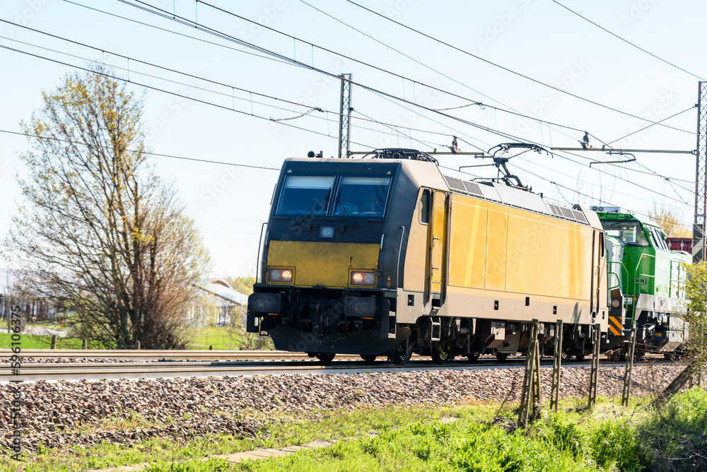 Fototapeta premium Powerful electric locomotive pulling a cargo train on a suny spring day