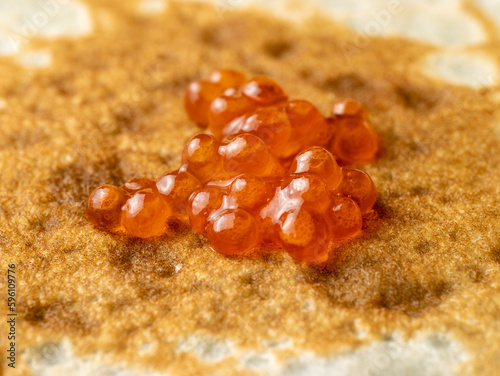 Red fish caviar on fried dough pancake close-up