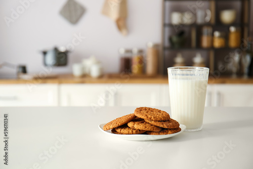 Plate with cookies and glass of milk on table in modern kitchen photo