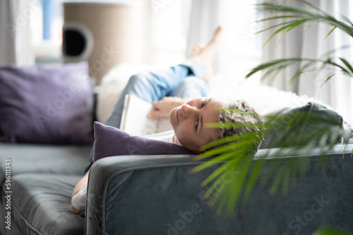 A woman is sitting on the couch reading a book