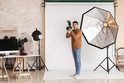 Young male photographer with professional camera in studio