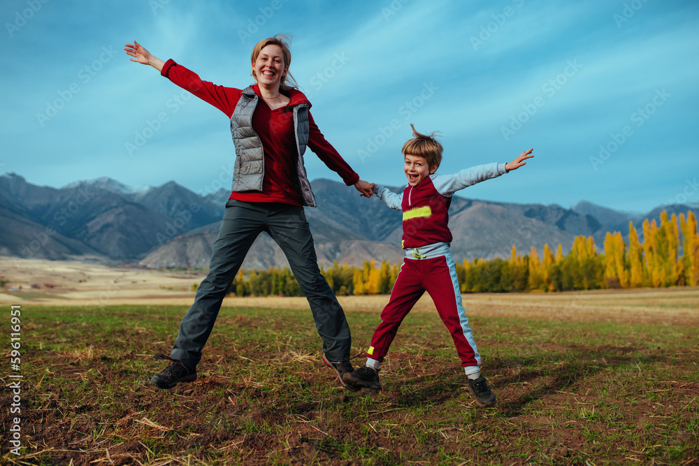 Happy mother and son jumping on mountains background
