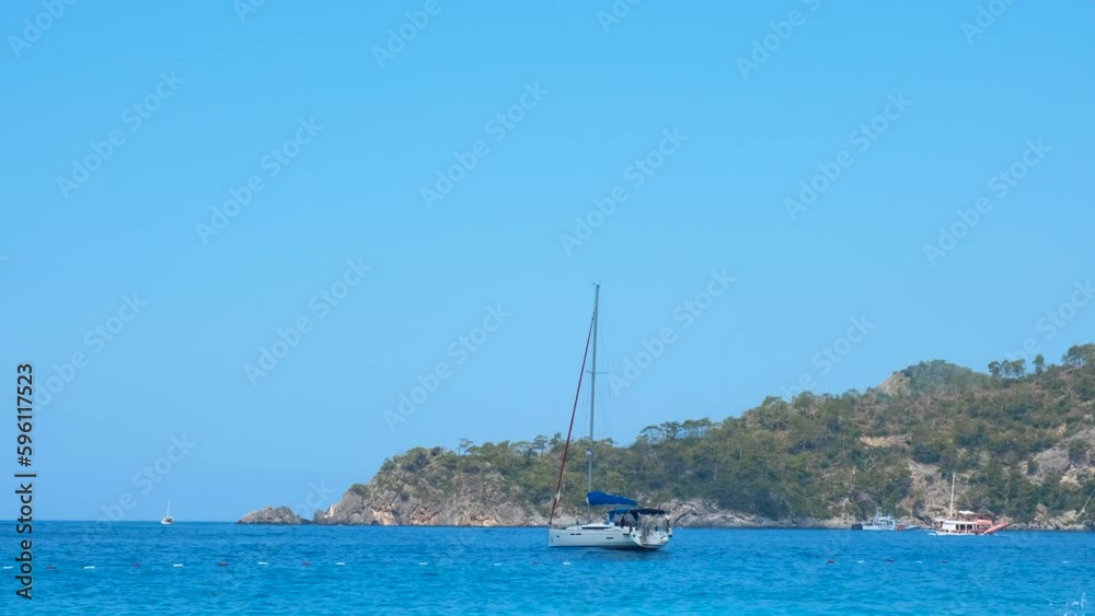 No sail yacht moored by sunny coastline. A view of no sails yacht stopped by the sea shore against tropical coast in the sun light. No sail yacht moored by sunny coastline. A view of no sails yacht stopped by the sea shore against tropical coast in the sun light.