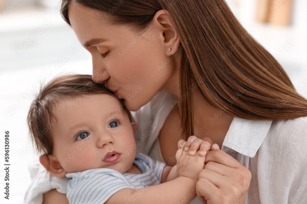 Happy mother kissing her little baby indoors, closeup Happy mother kissing her little baby indoors, closeup