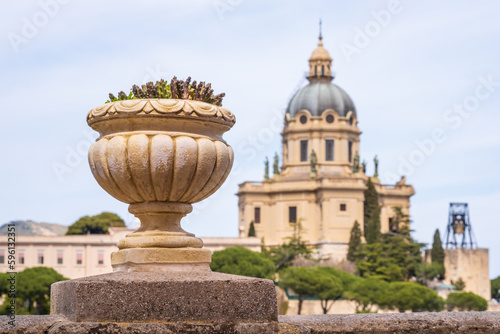 View of Messina on Sicily island, Italy. Succulent plant in cement pot and Votive Temple of Christ the King or Tempio di Cristo Re on hill over town as memorial to Italian soldiers © Julia Lavrinenko