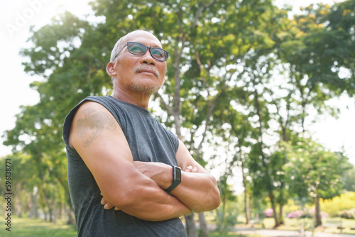Fototapeta Naklejka Na Ścianę i Meble -  Portrait of Happy and healthy Asian Chinese senior man with arms crossed at park outdoor. Male smiling relaxing, exercising.