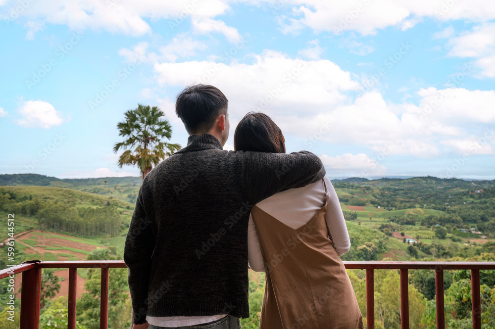 Young asian couple embracing and admire on mountain hill in countryside during vacation