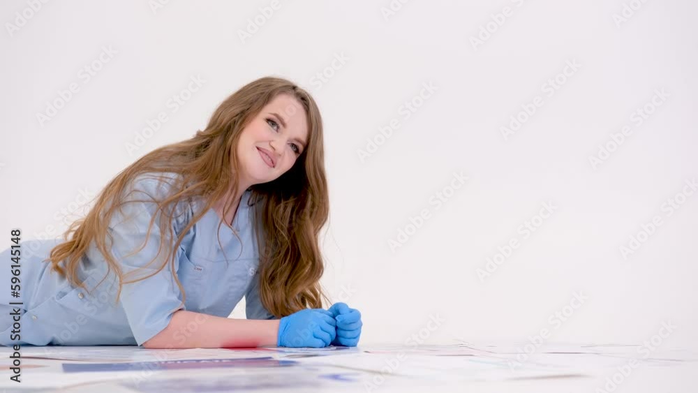 a young woman in blue clothes and gloves with flowing long hair lies in a studio on a white floor around scattered documents paper certificates work rest architect women working a young woman in blue clothes and gloves with flowing long hair lies in a studio on a white floor around scattered documents paper certificates work rest architect women working