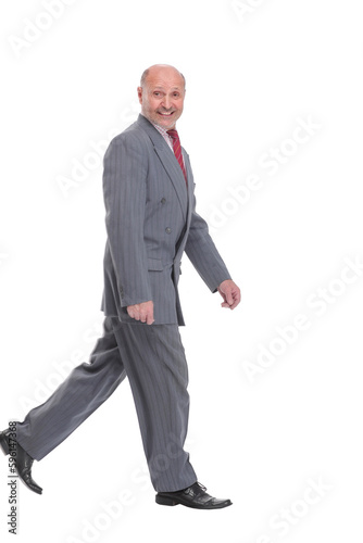 side view full length photo of a mid aged business man walking forward and looking away