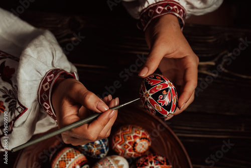 Ukrainian woman painting traditional ornamets on Easter egg - pysanka photo