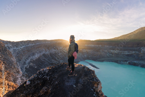 female mountaineer contemplating the Poas Volcano Crater Lagoon at sunrise surrounded by volcanic rocks in Poas Volcano National Park in Alajuela province of Costa Rica © Saintdags