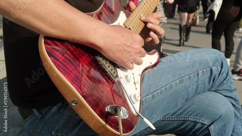 A guitarist is playing an electric guitar in two times slow motion in the street. Close-up view of hands playing an electric guitar.