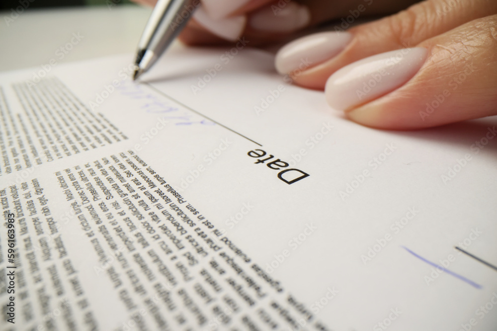 Woman writes date above line after signing contract papers Woman writes date above line after signing contract papers