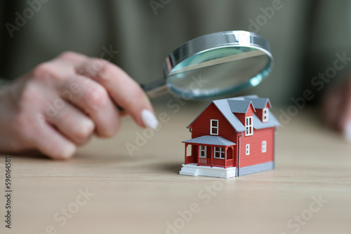 Woman holds magnifier glass above small model of townhouse photo