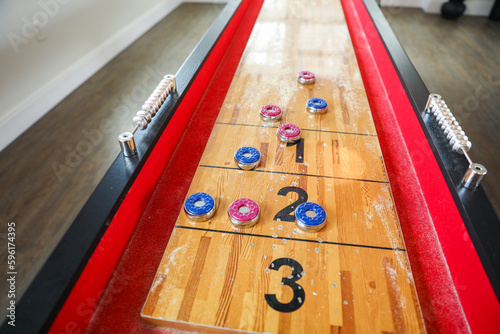 Shuffleboard is a game of precision and strategy, where players slide weighted discs down a narrow court to reach scoring areas Fototapeta