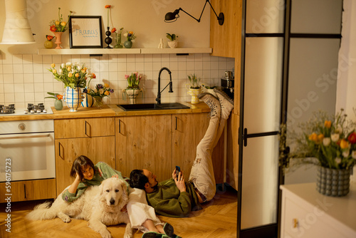 Young couple sit relaxed together with a cute dog on kitchen at home. Home coziness and domestic lifestyle concept photo