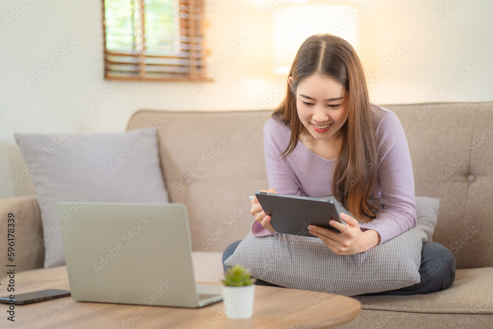 Young Asian graphic designer working on graphics tablet in her working space. Young college students reading somthing from her tablet. Young Asian graphic designer working on graphics tablet in her working space. Young college students reading somthing from her tablet.