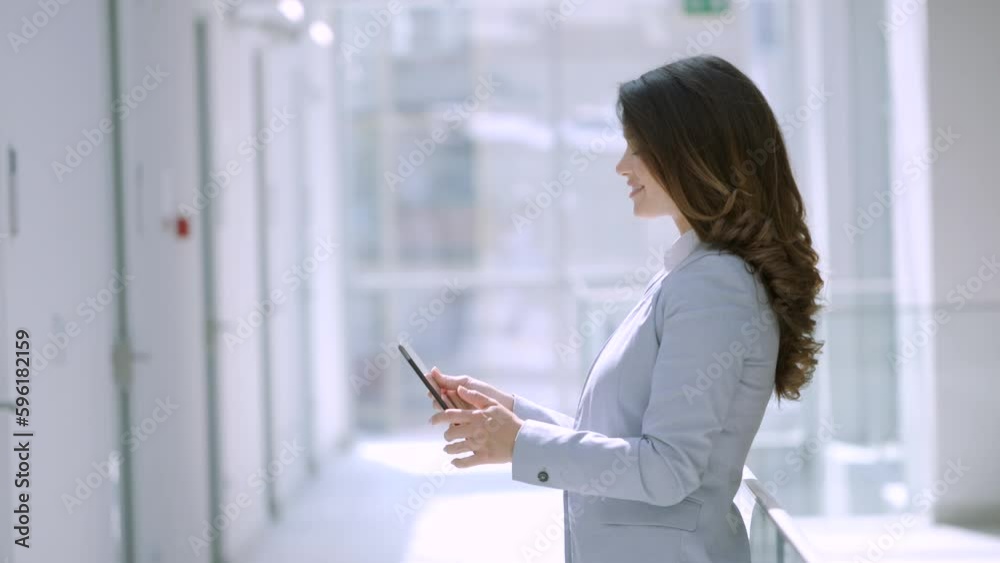 Pretty young woman working on digital tablet in the office hallway