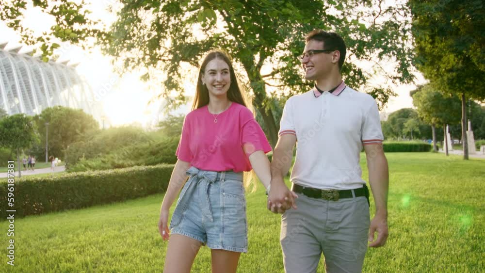 Cheerful boyfriend and girlfriend enjoying sunny day in beautiful city park with vibrant greenery. Young caucasian couple strolling around nice, green park. High quality 4k footage Cheerful boyfriend and girlfriend enjoying sunny day in beautiful city park with vibrant greenery. Young caucasian couple strolling around nice, green park. High quality 4k footage