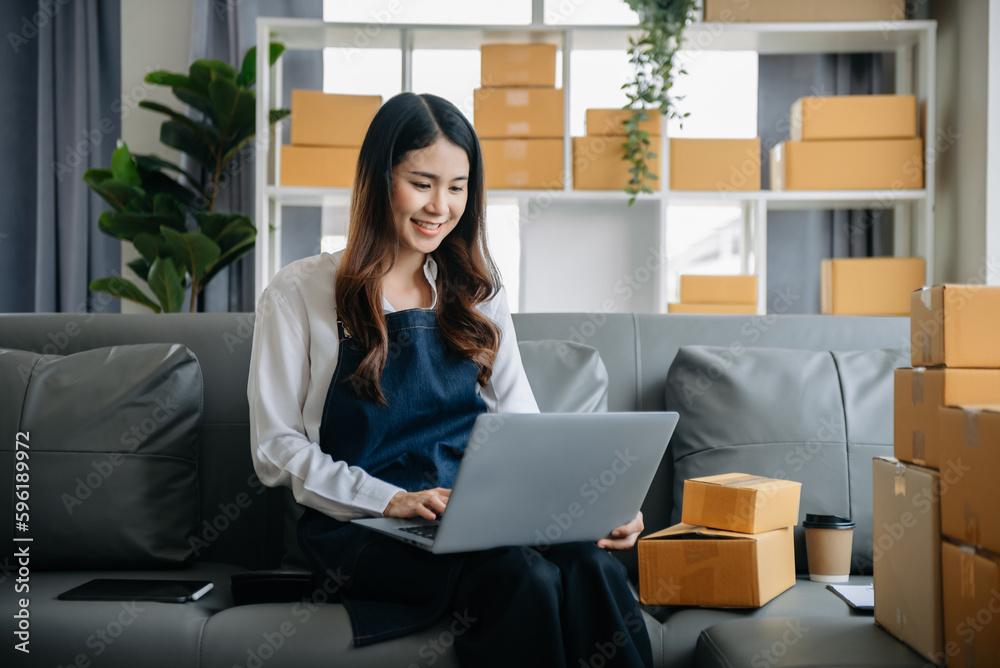 .Young business owner woman prepare parcel box and standing check online orders for deliver to customer on tablet, laptop Shopping Online concept. .Young business owner woman prepare parcel box and standing check online orders for deliver to customer on tablet, laptop Shopping Online concept.