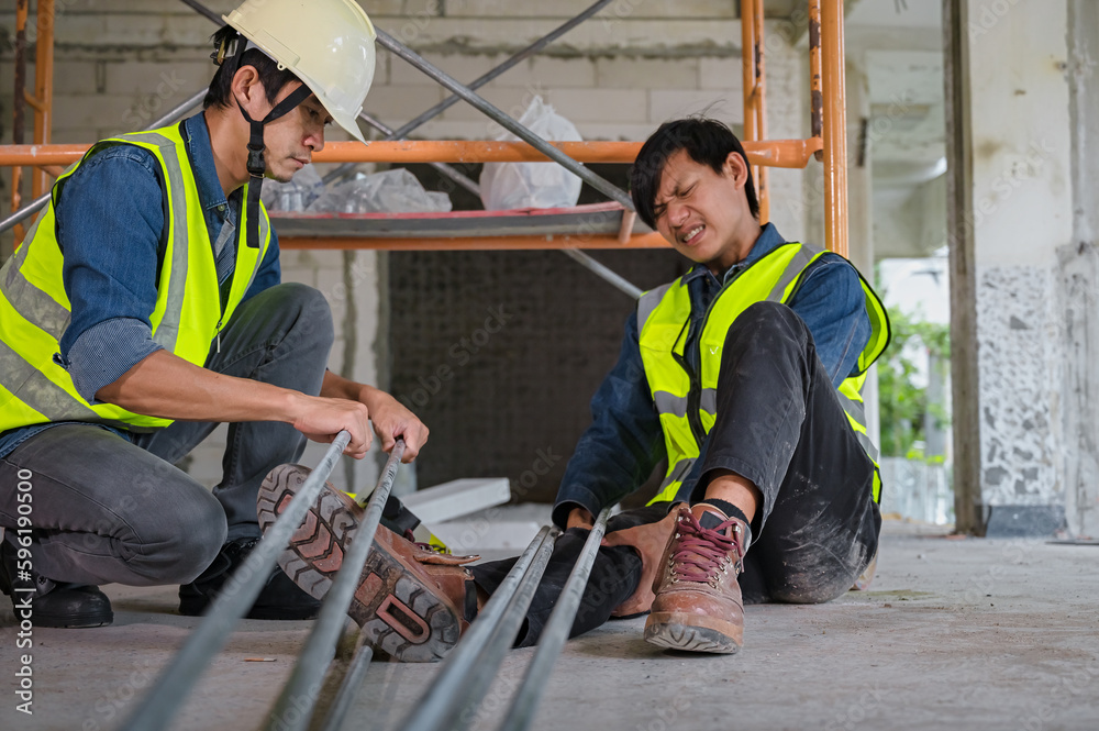 Young Asian builder falls from a height at a construction site. An engineer supervising the construction came to the aid of a construction worker who fell from a height with knee and leg injuries. Young Asian builder falls from a height at a construction site. An engineer supervising the construction came to the aid of a construction worker who fell from a height with knee and leg injuries.