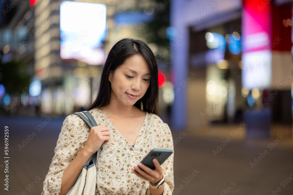 Woman use of mobile phone in city at night