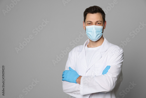 Doctor or medical assistant (male nurse) in uniform with protective mask on light grey background. Space for text