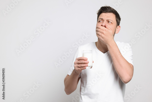 Man with glass of milk suffering from lactose intolerance on white background  space for text