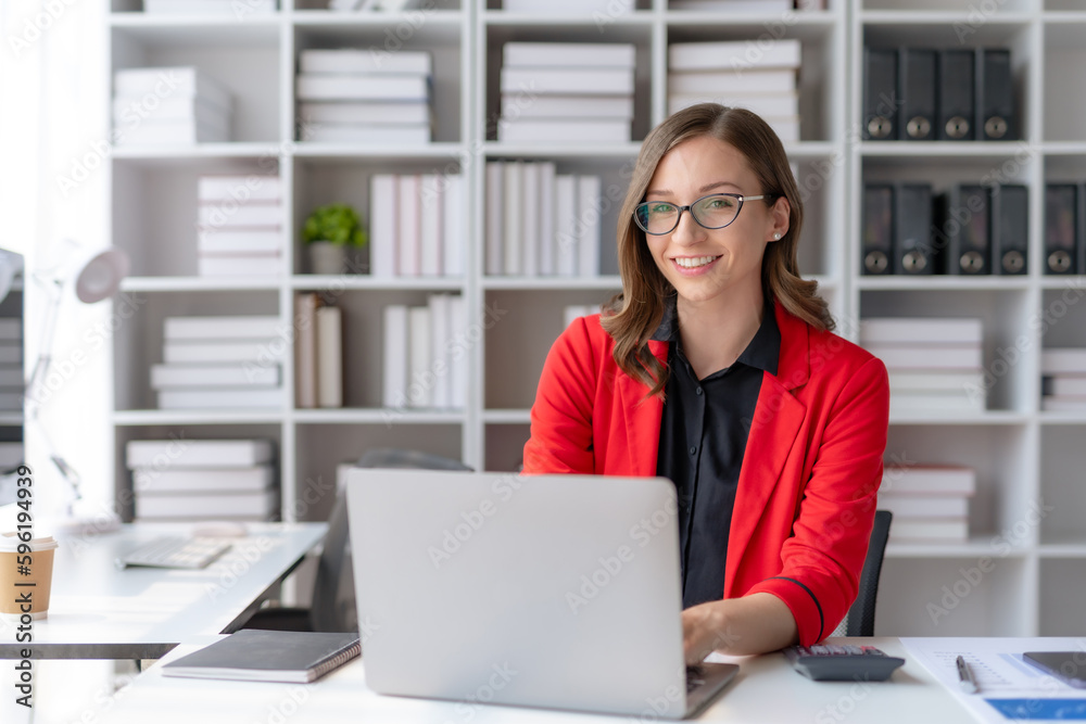 Charming businesswoman sitting working on laptop computer in office. Charming businesswoman sitting working on laptop computer in office.