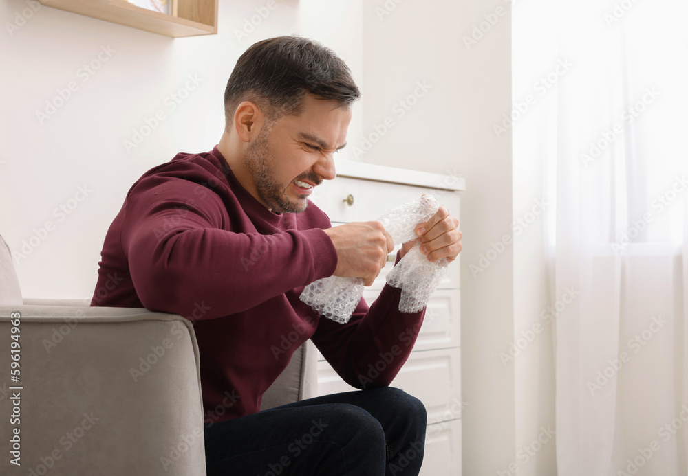 Emotional man with bubble wrap indoors. Space for text Emotional man with bubble wrap indoors. Space for text