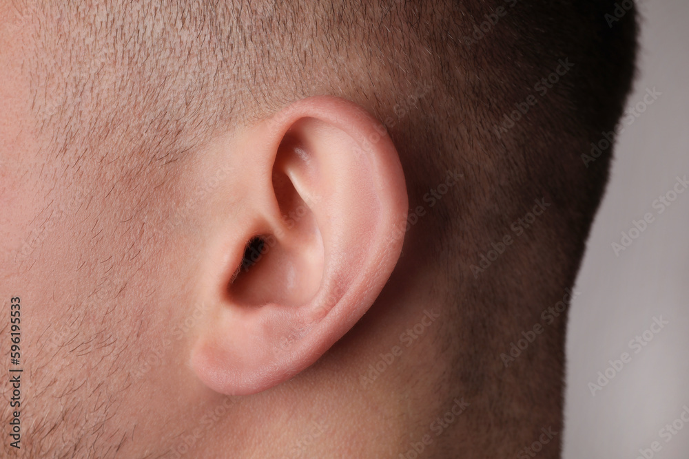 Man on grey background, closeup of ear Man on grey background, closeup of ear