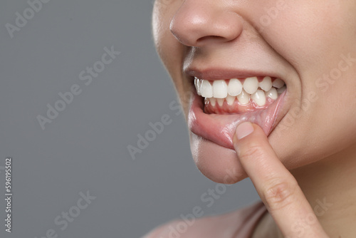 Woman showing healthy gums on gray background, closeup. Space for text