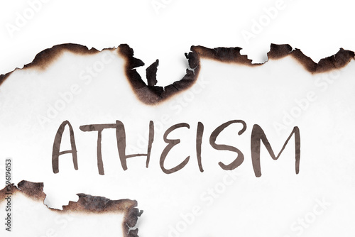 Word Atheism on paper with burnt borders. Philosophical or religious position