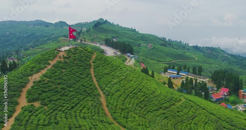 Drone flies close to Nepal's flag fluttering proudly amidst the lush green tea gardens of Kanyam, Ilam. A touristic destination, this shot captures the beauty of Nepal's natural landscape and beauty. photo