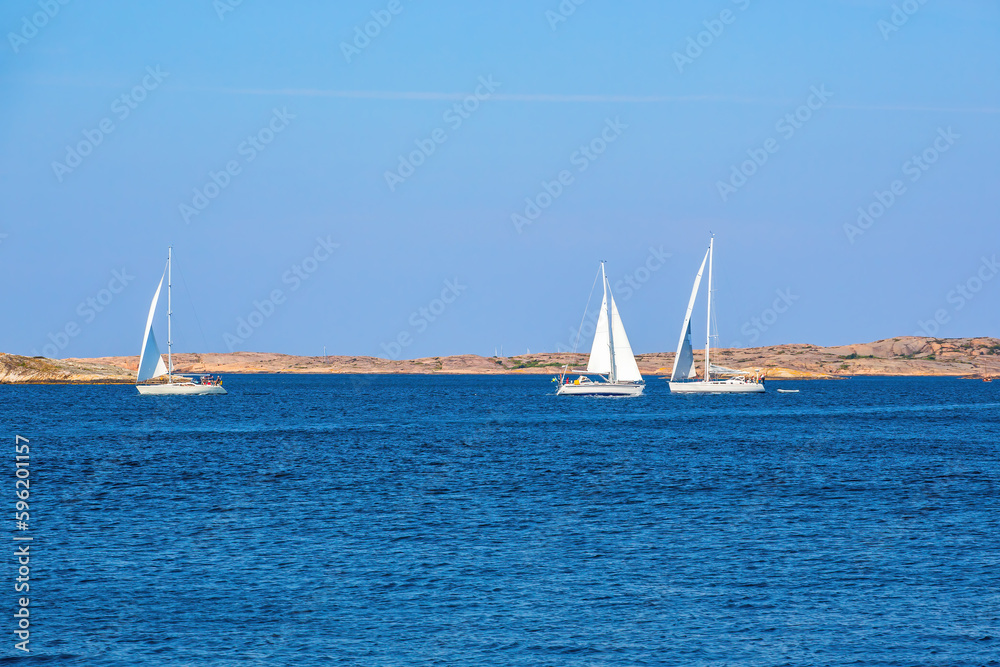 Sailboats on the sea at a rocky coast