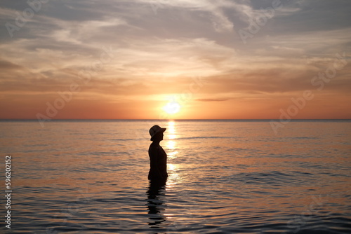 woman standing in the sea during the sunset