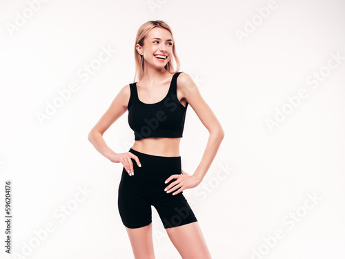 Young beautiful smiling blond female in black cycling shorts clothes. Sexy carefree woman posing on white background in studio. Positive model having fun indoors. Cheerful and happy