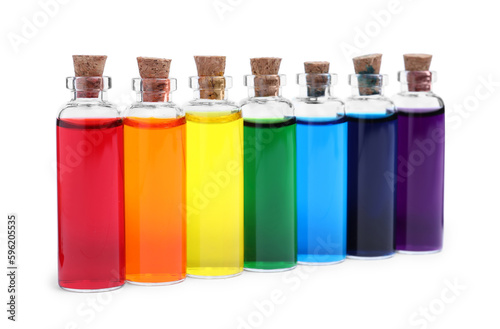 Glass bottles with different food coloring on white background