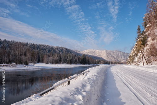 Altai winter road and river Biya in winter season. Banks of river are covered by ice and snow.