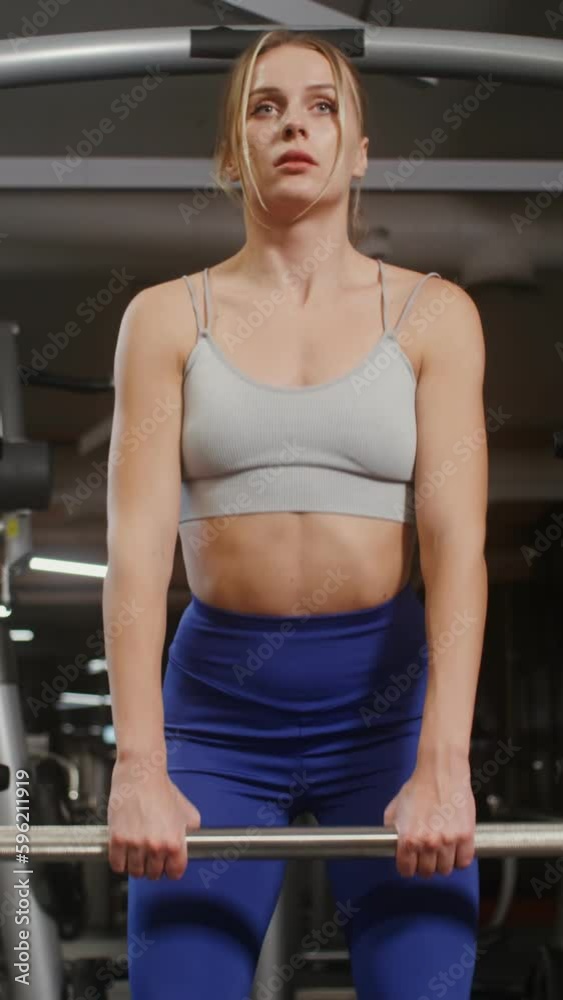 Young beautiful woman with athletic physique, dressed in a sports uniform, doing bends with a barbell on the exercise machine, doing in the gym. Front videography, close-up Young beautiful woman with athletic physique, dressed in a sports uniform, doing bends with a barbell on the exercise machine, doing in the gym. Front videography, close-up