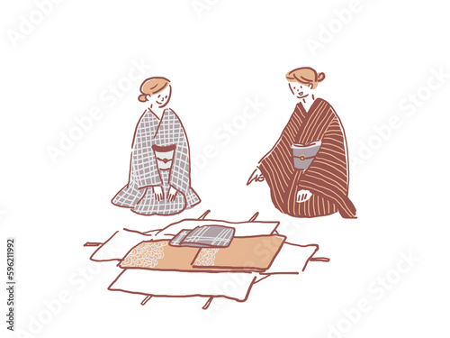 たとう紙を広げて着物と帯を見る着物を着た女性二人 photo