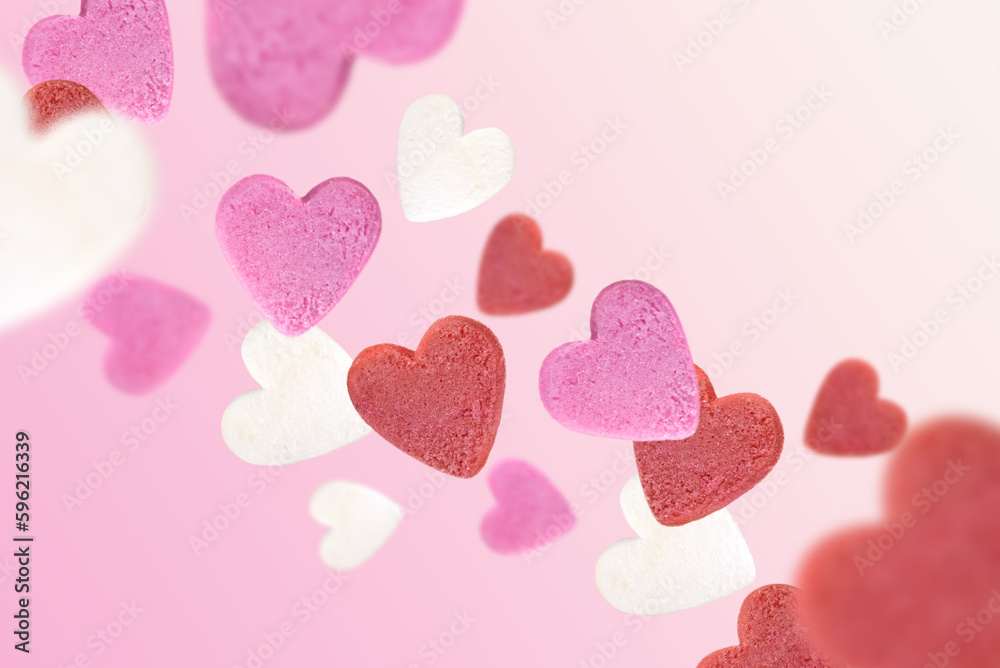 Levitation of sugar hearts on a pink background.
