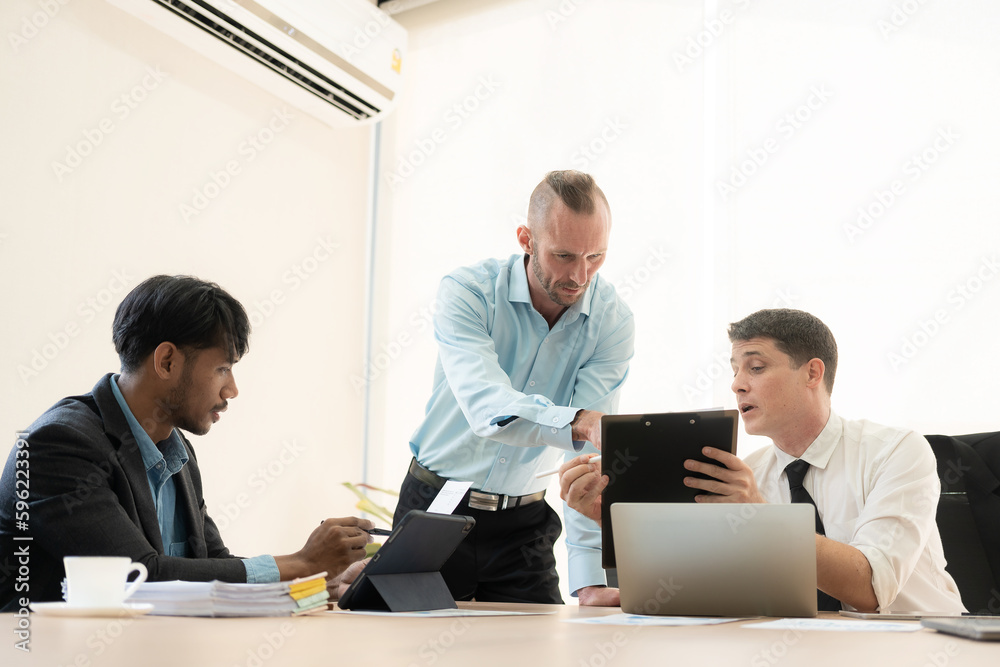 Investment advisor meeting of three businessmen analyzing company financial report, balance sheet, working with chart papers for stock market. Office Investment advisor meeting of three businessmen analyzing company financial report, balance sheet, working with chart papers for stock market. Office