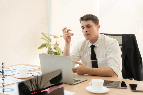 Businessman or accountant holding pen working with laptop on business financial data, accounting graph document and calculator at office, online business meeting concept