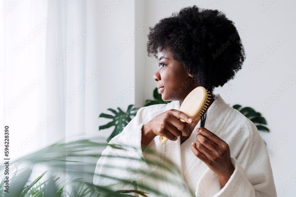 © Westend61 - Woman wearing bathrobe combing hair at home © Westend61 - Woman wearing bathrobe combing hair at home